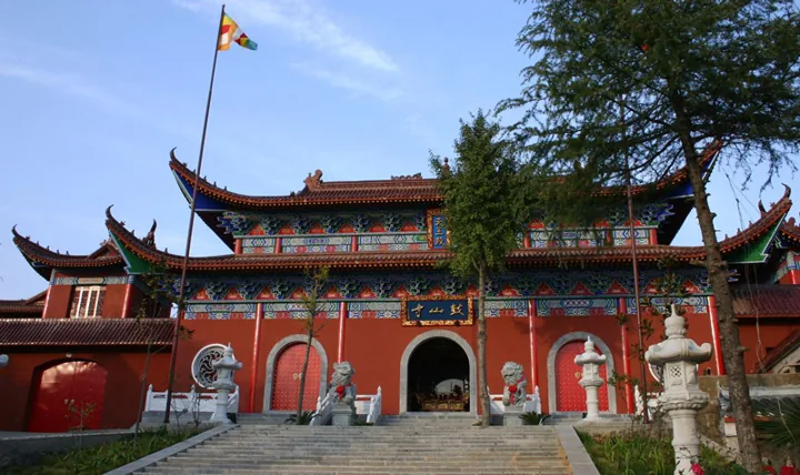 Red temple gateway with ornate eaves, stone stairs and guardian lions.