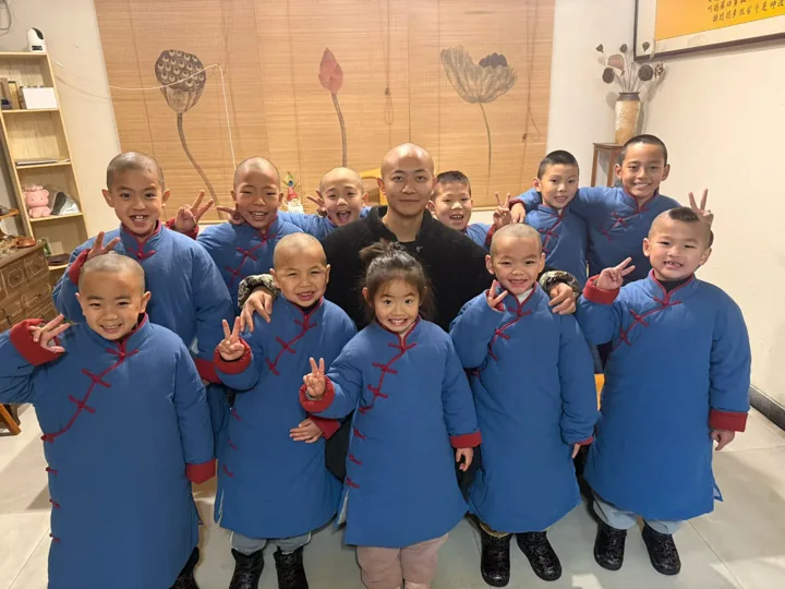 Young students pose together with their teacher inside a room.