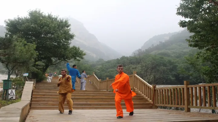 A teacher in orange and students practise on a mountain terrace.