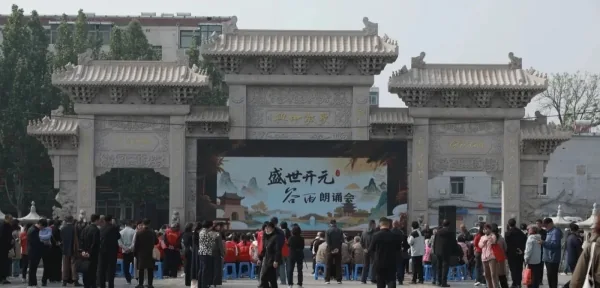 Visitors gather at a stone temple gate beneath a Chan event banner.