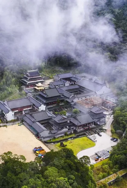 An aerial view of the temple complex amid forest and drifting cloud.