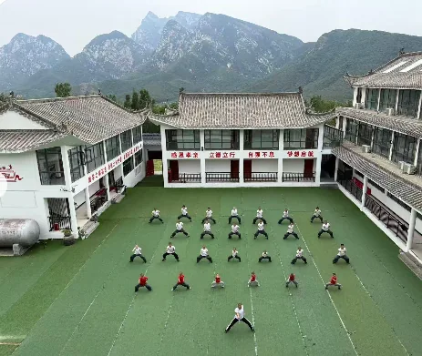 Students practise in a green courtyard surrounded by white school buildings.