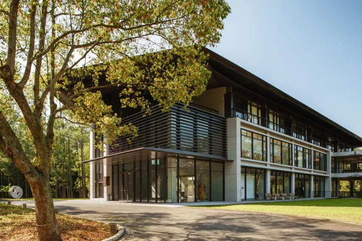 Yongshan Hall's glass and wood facade amid trees at Mabuville.
