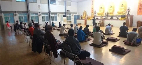 Retreat participants practise together in a bright meditation hall.