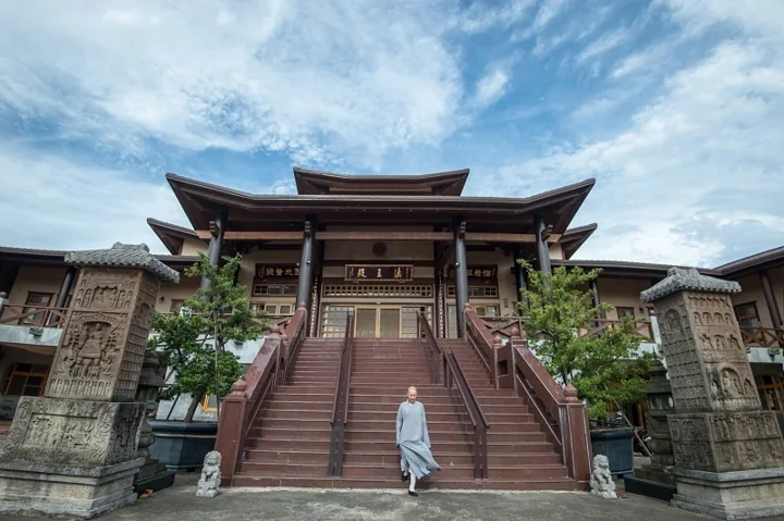 A monastic walks up the stairs of a traditional hall at Yuan Kuang Buddhist Institute.