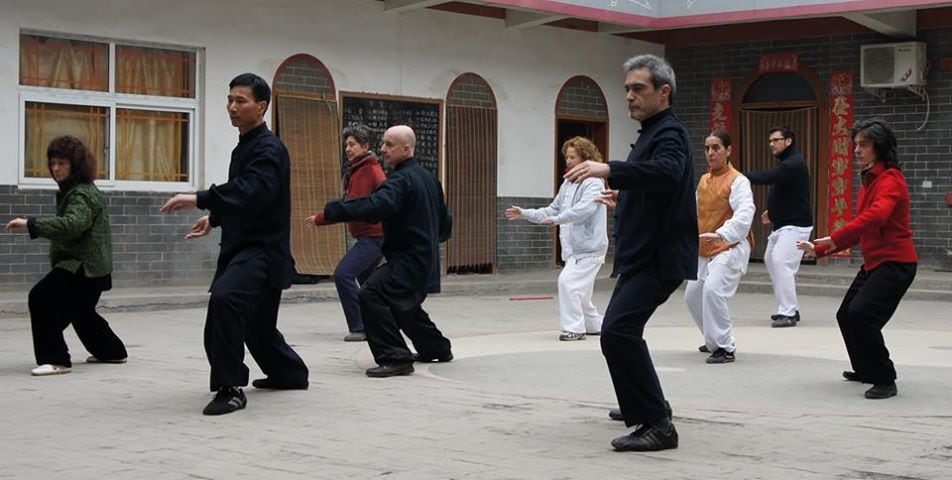 Chen Bing führt erwachsene Schüler in einem Hof durch eine Tai-Chi-Form.