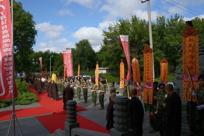 A ceremonial procession enters temple grounds lined with banners.