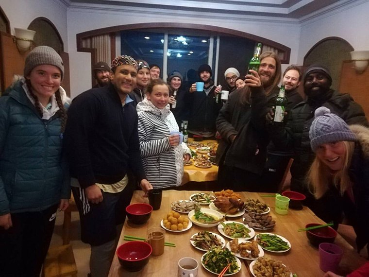 Students gather around a table of shared dishes.