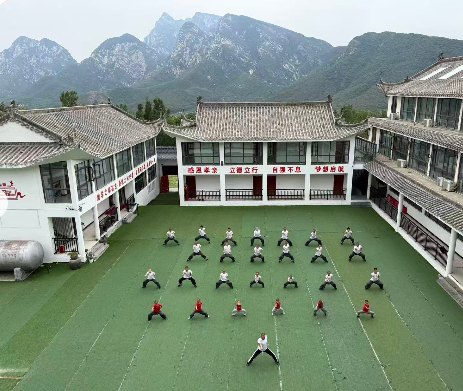 Students practise in a green courtyard surrounded by white school buildings.