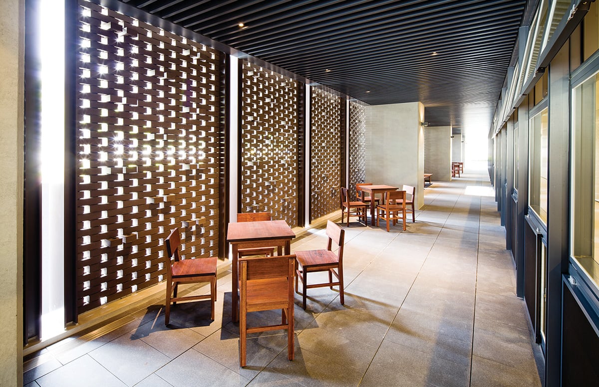 An empty walkway where brick screens cast patterned light.