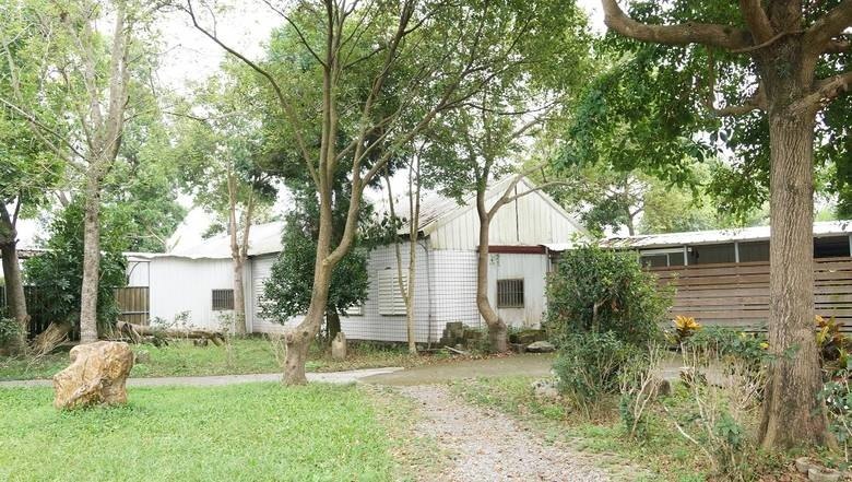 Earlier Dhammodaya hall beside trees and a grassy path.