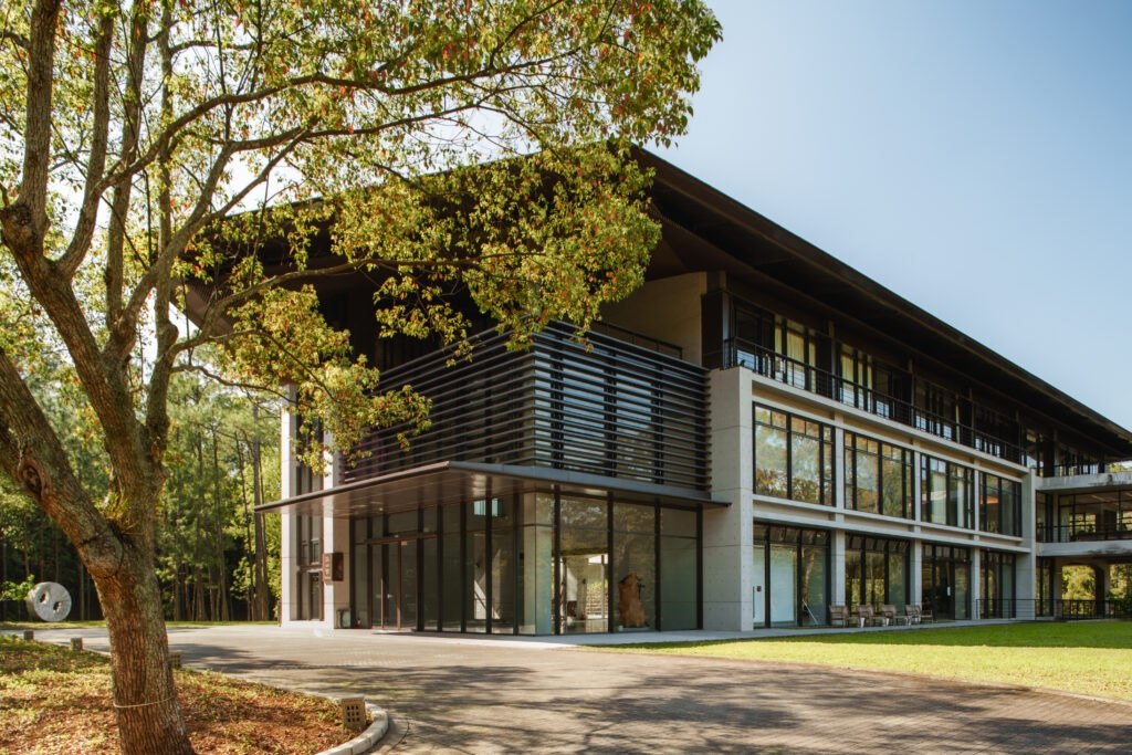 Glas- und Holzfassade der Yongshan-Halle zwischen Bäumen in Mabuville.