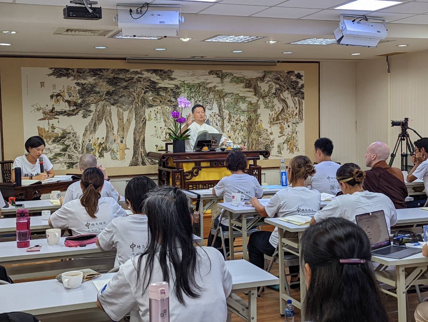 学生围坐桌边听佛学课。